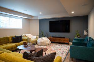 Angled view from the couch in the living room looking at the tv on an accent wall and window.