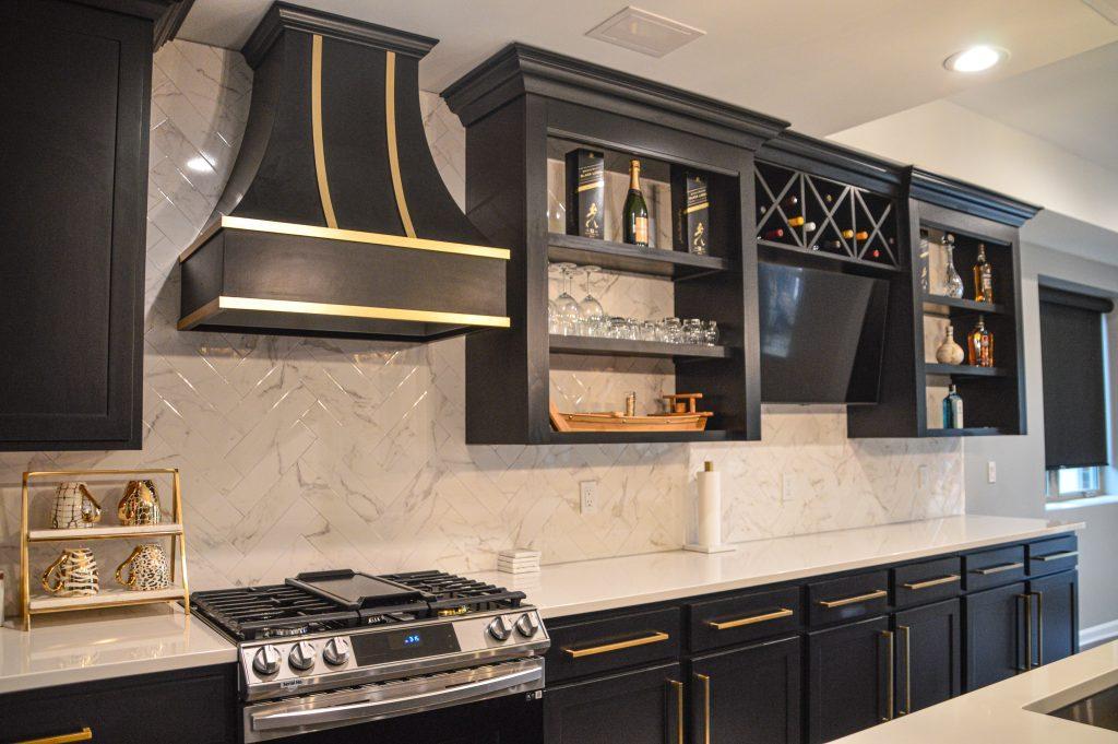 Closer look of back counter in kitchen area with black cabinets and gold hardware, white countertop and gas stove.