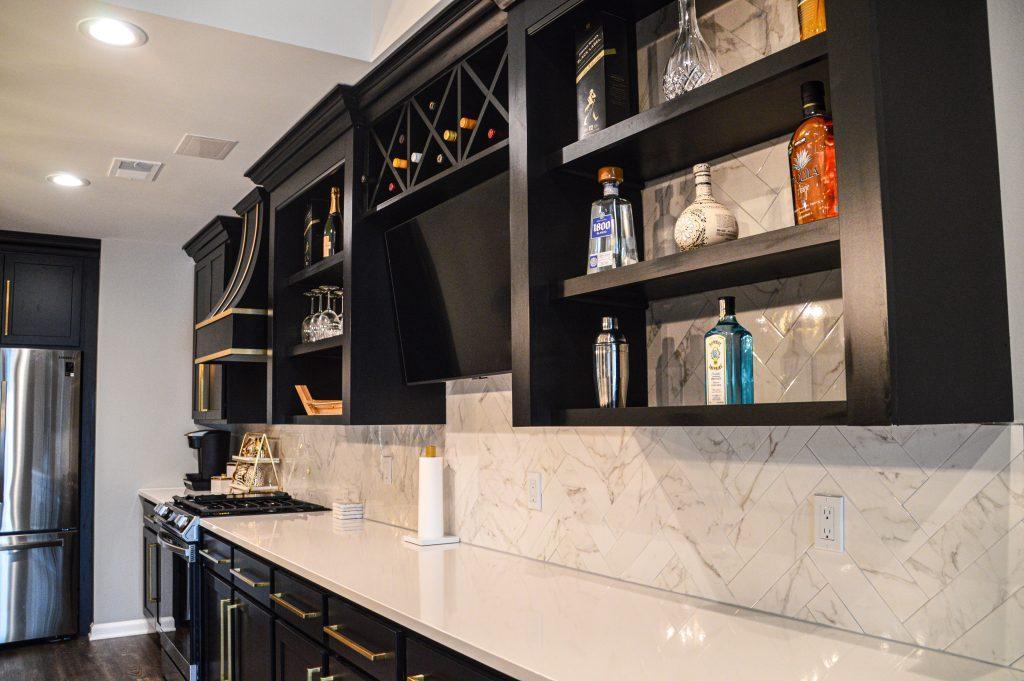 Closer look of back counter in kitchen area with black cabinets and gold hardware, white countertop and gas stove.