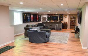 Finished basement living room and bar area with sport jerseys hanging on wall.