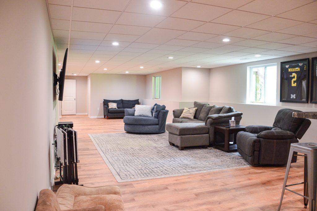 Finished basement living room area with multiple couches and chairs for sitting.