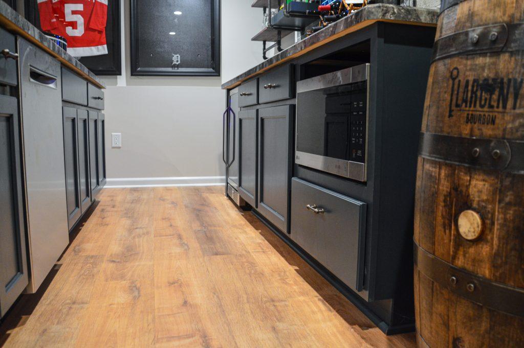 Blue cabinets with storage and microwave in bar area.