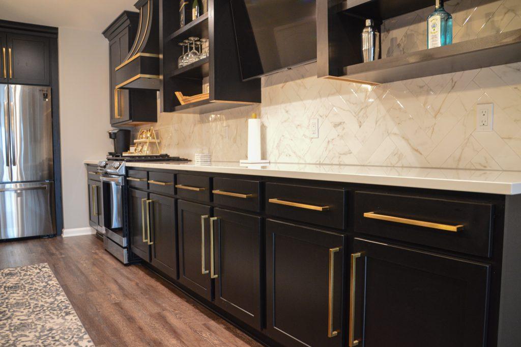 Back counter in kitchen area with black cabinets and gold hardware along with a white countertop.