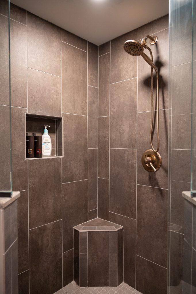 Closeup view of the tile in the walk-in shower with bench seating in corner in a finished basement bathroom.