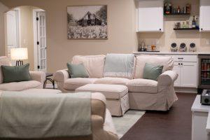 Finished basement living room area with dry bar in the background with spirits and snacks for watching movies.