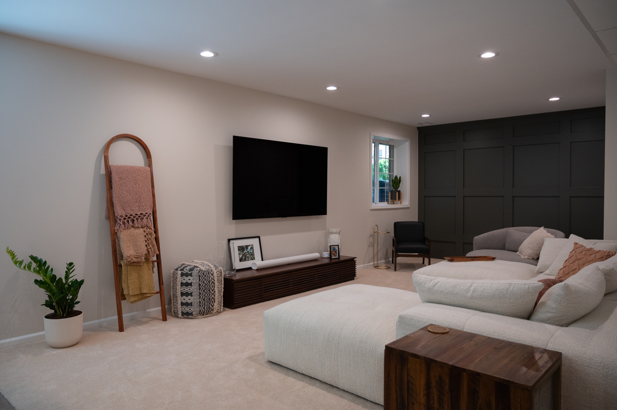 Photo of finished, furnished basement with earth tones and accent wall.