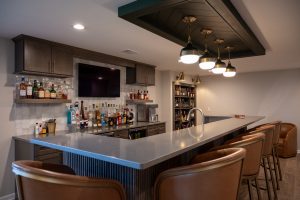 Newly installed countertop with drop lighting, accented by dark framing and shelving for storage