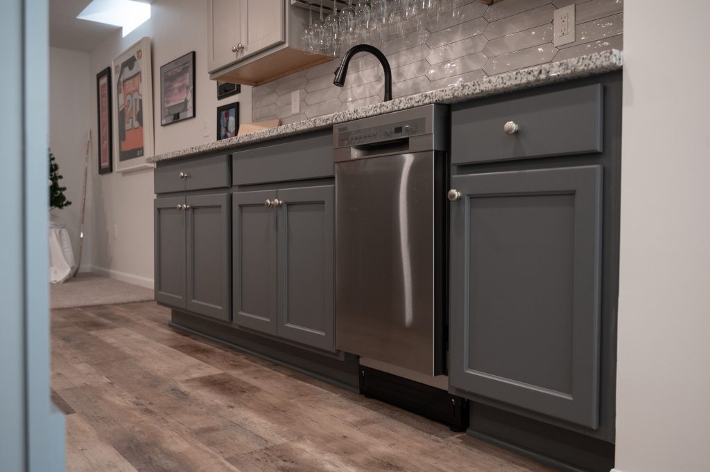 Sink with installed dishwasher and new cabinets in a finished basement