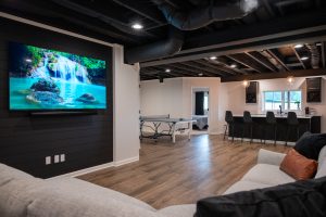 Stylish Basement Living Room with Black Painted Ceiling, Hardwood Floors, and Entertainment Bar Area